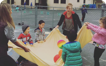 Children having fun playing with a big yellow sheet outdoors