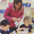 a woman and two children diligently working on a craft project together