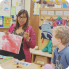 a woman patiently guides a child's hand as they learn to draw together