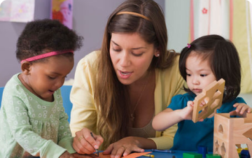 a woman and two children building with wooden blocks