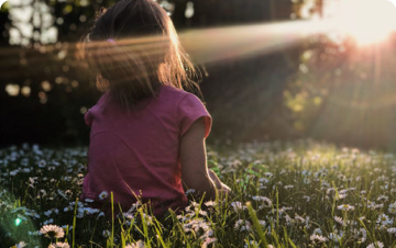 a young girl sitting in a colorful field of flowers, surrounded by vibrant blooms and enjoying nature