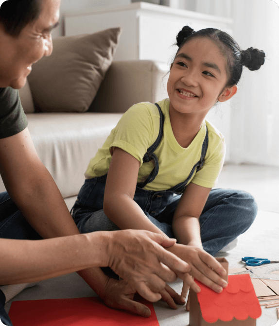 a young girl and her father are joyfully crafting a paper house together, showcasing creativity and bonding